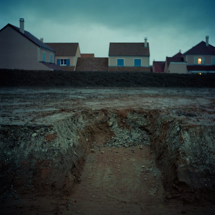 La nuit dans une banlieue paisible, on voit sur une parcelle encore vierge de maisons que la terre a été creusée...