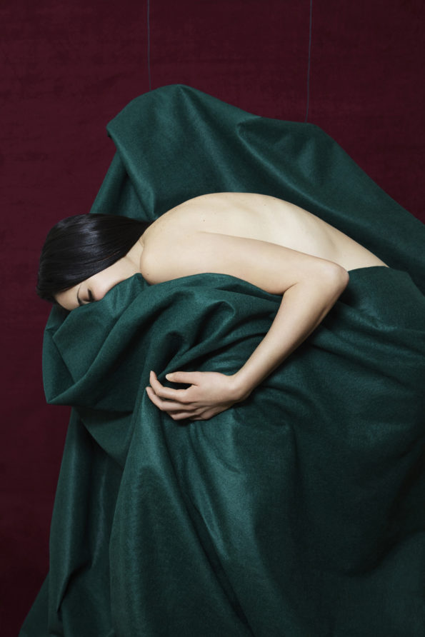 Femme arabe enveloppée dans une couverture verte, la couverture evoque une forme humaine. Consolation, peine, madone.